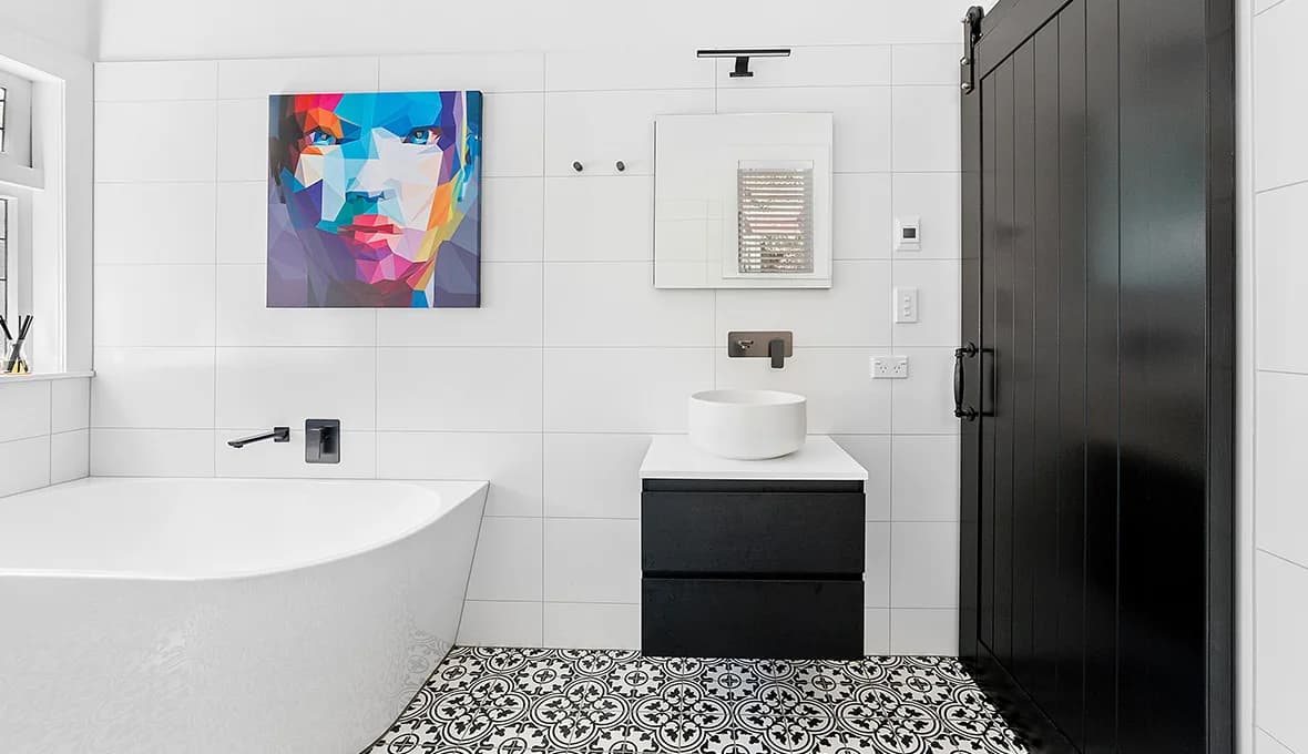Close-up of a matte black square rain head and handheld shower on a riser rail, mounted in a glass-walled shower.